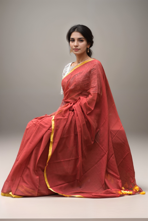 Woman in rust red mul cotton saree with yellow border from Mridula