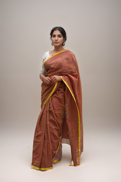 Woman in rust brown mul cotton saree with yellow border by Mridula